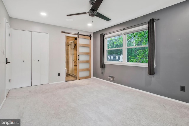unfurnished bedroom with a barn door, carpet flooring, baseboards, a closet, and recessed lighting