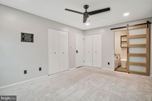 unfurnished bedroom with a barn door, multiple closets, carpet, baseboards, and recessed lighting