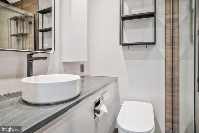 full bath featuring tiled shower, vanity, and toilet