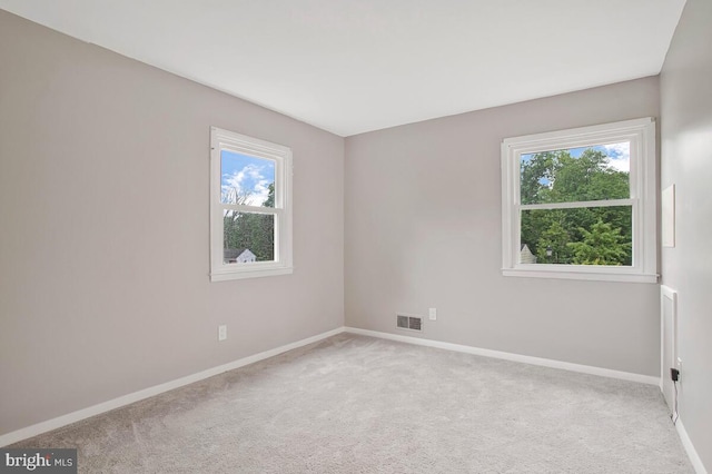 unfurnished room with healthy amount of natural light, baseboards, and carpet