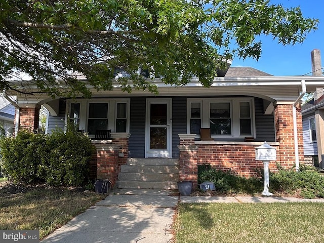 bungalow-style home with covered porch and brick siding
