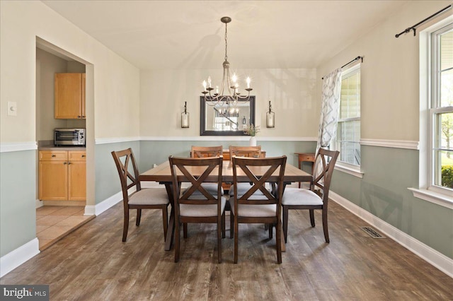 dining room featuring a chandelier, wood finished floors, and baseboards