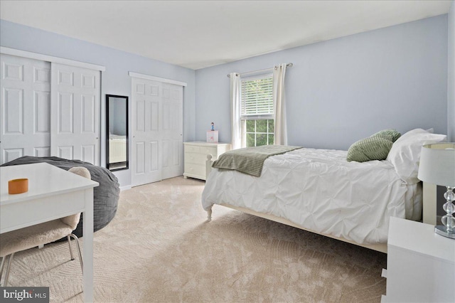 bedroom with multiple closets and light colored carpet