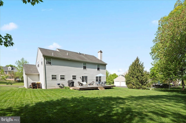 back of property with a yard, a wooden deck, and a chimney