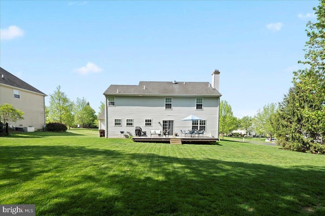 back of property with a lawn, a wooden deck, and a chimney