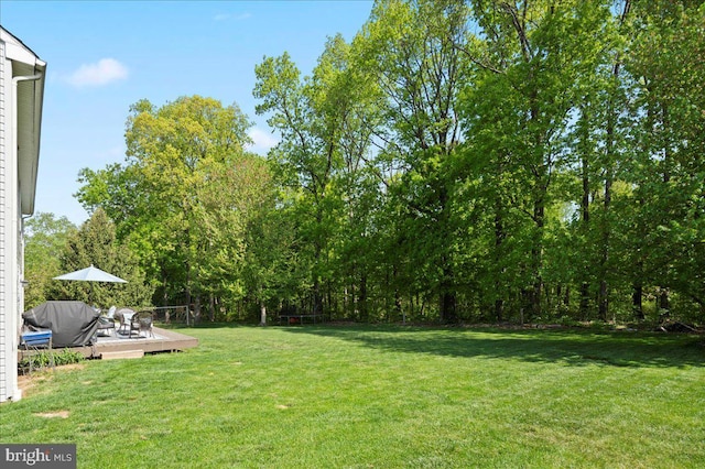 view of green lawn featuring a wooden deck