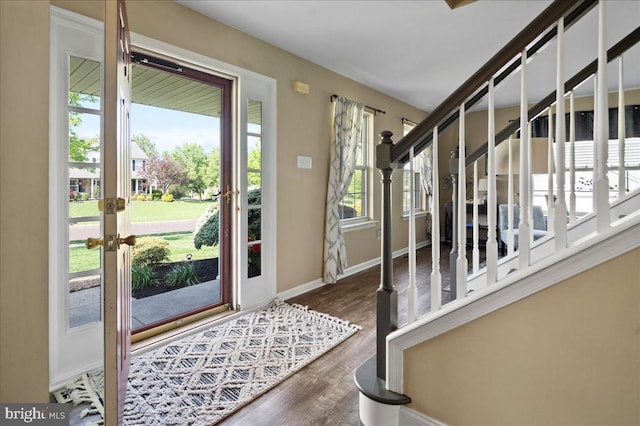 foyer entrance with plenty of natural light, wood finished floors, stairs, and baseboards