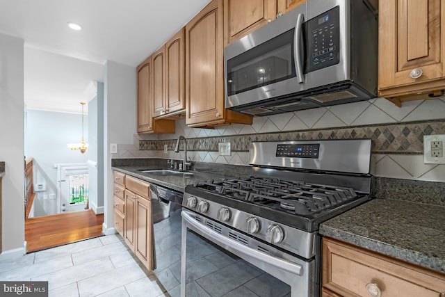 kitchen with appliances with stainless steel finishes, a sink, light tile patterned floors, and decorative backsplash