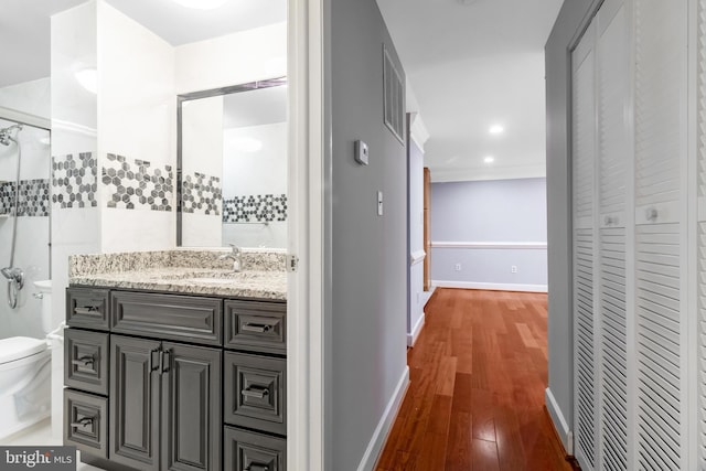 bathroom featuring toilet, wood finished floors, vanity, baseboards, and a closet