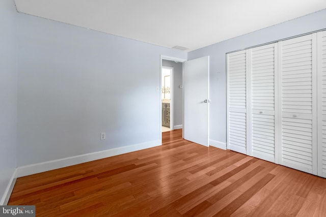 unfurnished bedroom featuring light wood finished floors, baseboards, and a closet