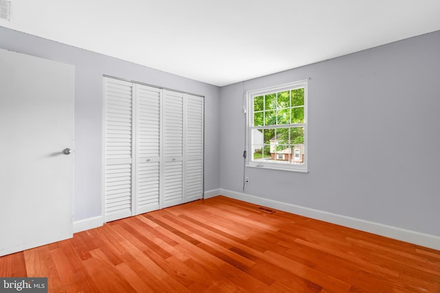 unfurnished bedroom with wood finished floors, baseboards, and a closet