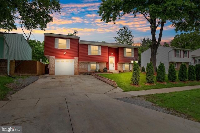 split foyer home featuring an attached garage, driveway, and brick siding