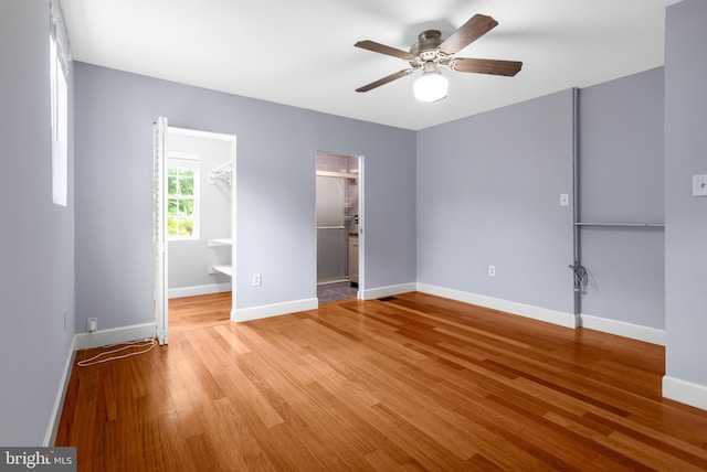 unfurnished bedroom featuring light wood-type flooring, a spacious closet, and baseboards