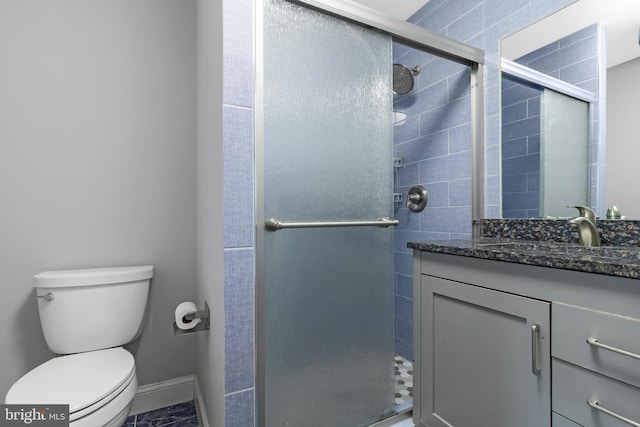 full bathroom featuring a stall shower, toilet, vanity, and baseboards