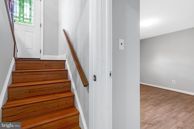 stairway with wood finished floors and baseboards