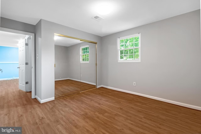 unfurnished bedroom featuring wood finished floors, baseboards, and a closet