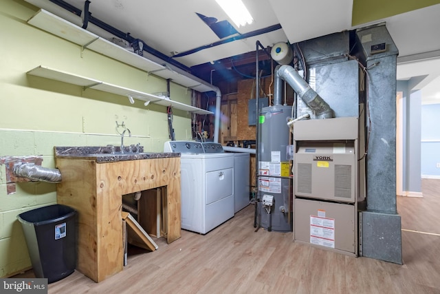 clothes washing area featuring water heater, wood finished floors, and washer and dryer