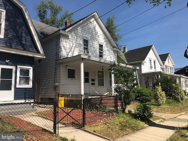 view of front of property featuring covered porch, a fenced front yard, and a gate