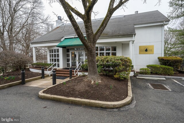 1655 Oakwood Dr Unit N323, Narberth, PA 19072 - view of front of property featuring roof with shingles, uncovered parking, a chimney, and stucco siding