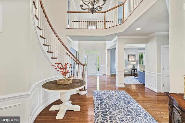 entrance foyer with a high ceiling, a decorative wall, stairs, crown molding, and a chandelier