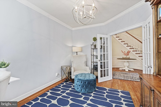 living area with wood finished floors, a chandelier, stairway, and crown molding