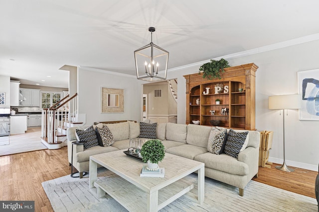 living room with stairway, light wood-style floors, crown molding, a chandelier, and baseboards