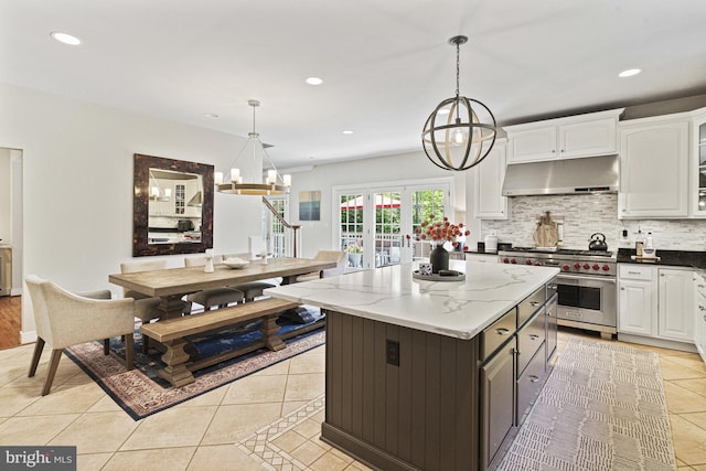 kitchen featuring designer stove, under cabinet range hood, a chandelier, light tile patterned floors, and recessed lighting