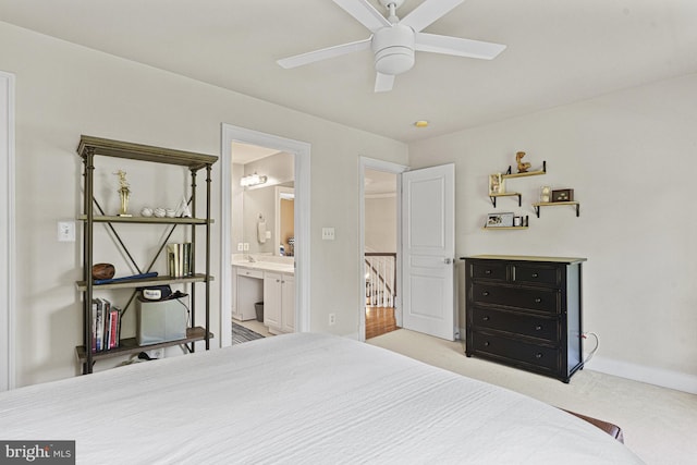 bedroom featuring light carpet, connected bathroom, baseboards, and ceiling fan