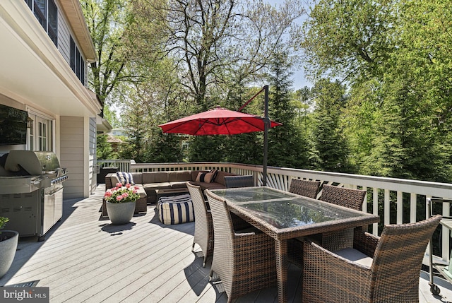 wooden deck with outdoor dining space, an outdoor hangout area, a grill, and view of wooded area