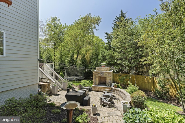 view of yard with an outdoor stone fireplace, fence, a patio area, and stairs