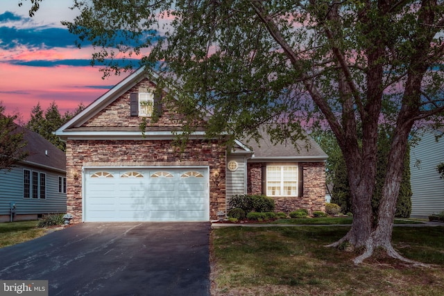 traditional-style home with stone siding, driveway, a garage, and a front yard