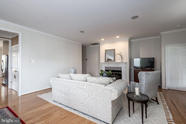 living area with light wood finished floors, baseboards, a high end fireplace, ornamental molding, and recessed lighting