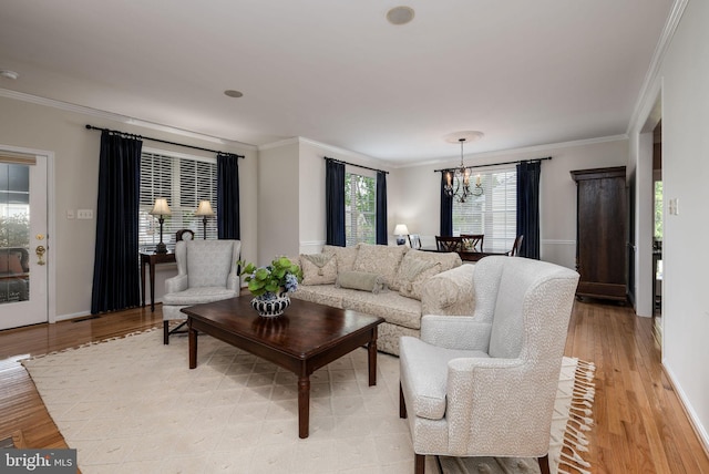 living room with a chandelier, crown molding, light wood-style floors, and baseboards