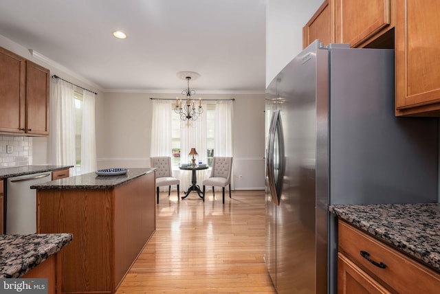 kitchen with stainless steel appliances, crown molding, brown cabinetry, a chandelier, and light wood-style floors
