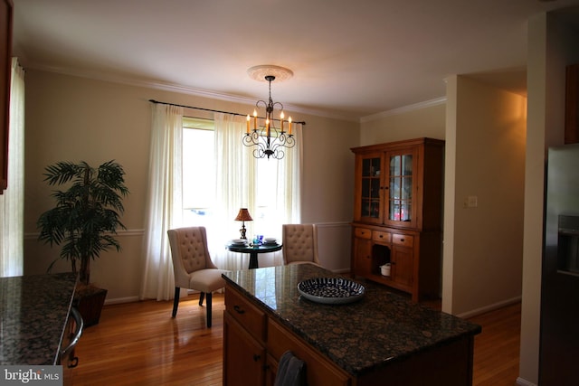 dining area featuring wood finished floors, a chandelier, ornamental molding, and baseboards