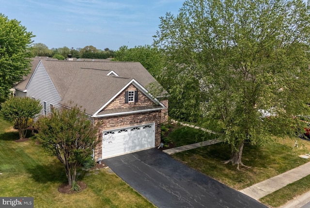 view of front facade with stone siding, asphalt driveway, a front yard, roof with shingles, and an attached garage