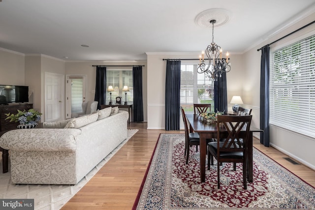dining space featuring light wood-style floors, a chandelier, healthy amount of natural light, and ornamental molding