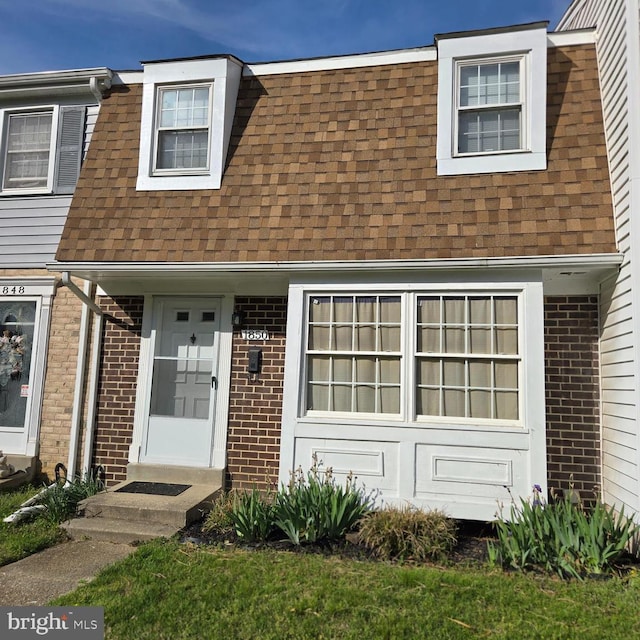 townhome / multi-family property featuring a shingled roof and brick siding