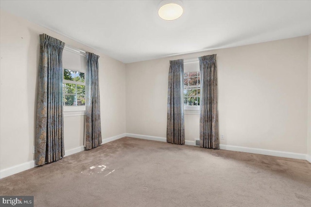 spare room featuring healthy amount of natural light, carpet, and baseboards