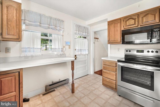kitchen with stainless steel electric stove, black microwave, light floors, light countertops, and brown cabinetry