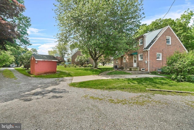 view of green lawn featuring a storage shed and an outbuilding