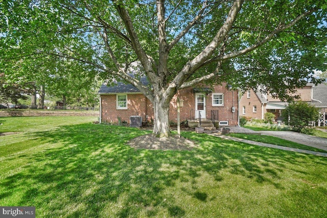 view of front of house featuring brick siding, a front lawn, and central AC unit