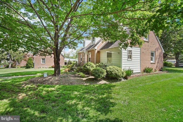 view of side of home with brick siding and a lawn