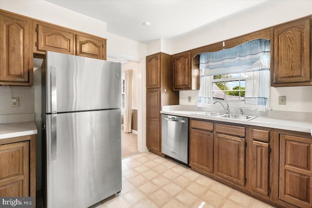 kitchen with stainless steel appliances, light flooring, a sink, and light countertops