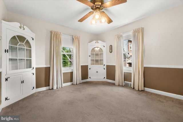 carpeted empty room featuring plenty of natural light, a ceiling fan, and baseboards