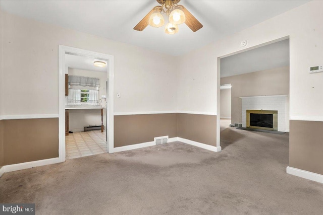 unfurnished living room featuring ceiling fan, carpet flooring, baseboards, and a brick fireplace