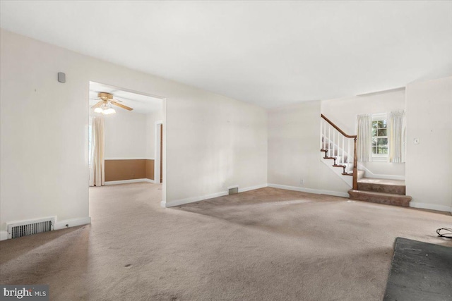 unfurnished living room featuring stairs, carpet flooring, ceiling fan, and baseboards