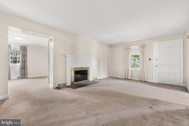 unfurnished living room featuring carpet flooring, plenty of natural light, and a brick fireplace