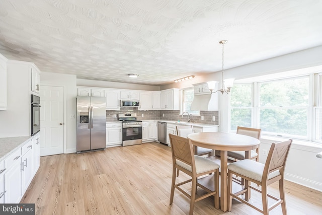 7290 Southern Maryland Blvd, Owings, MD 20736 - kitchen featuring appliances with stainless steel finishes, a sink, a chandelier, tasteful backsplash, and light wood-style floors