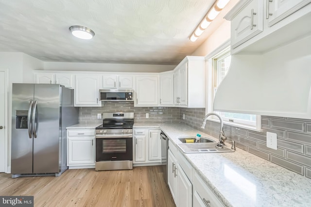 7290 Southern Maryland Blvd, Owings, MD 20736 - kitchen featuring appliances with stainless steel finishes, a sink, white cabinets, decorative backsplash, and light wood-style flooring